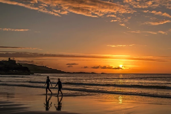 Couple walking along beach during sunset