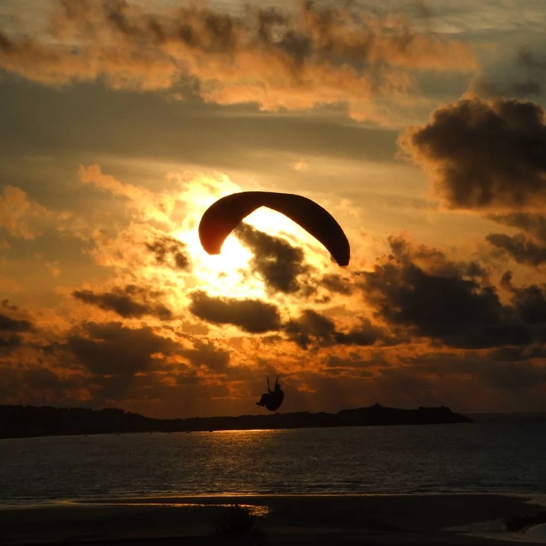 A paraglider flying into the sunset